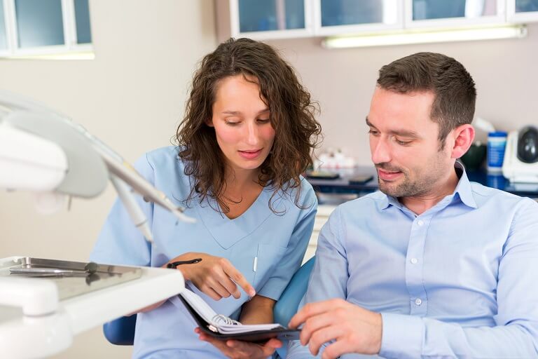 Dentista com agenda para consultório odontológico marcando horário com paciente.