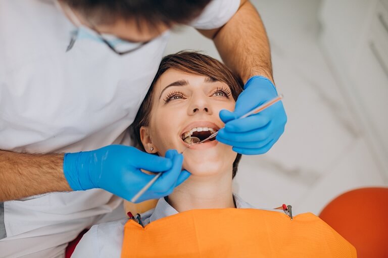 Ortodontista utilizando espelho para visualizar a boca de paciente.