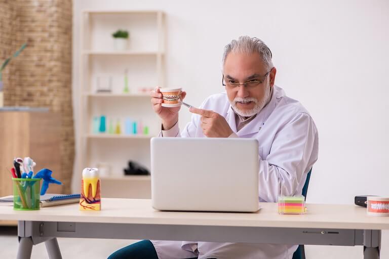 Dentista mostra modelo ao produzir conteúdo para educação do paciente.