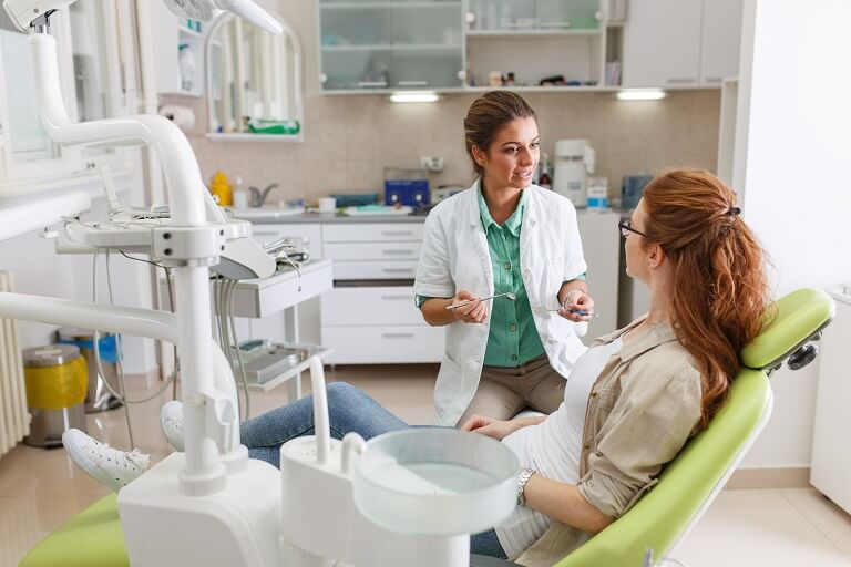 Dentista conversando com paciente em consultório.