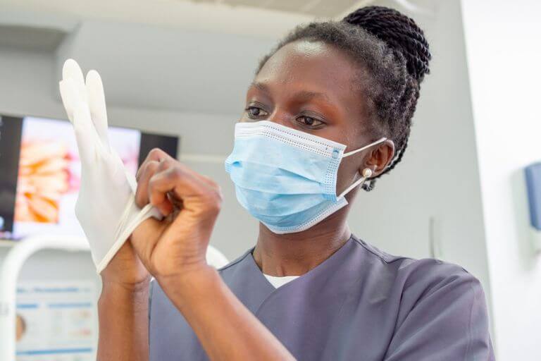 dentista colocando luvas para estabelecer práticas odontológicas com biossegurança